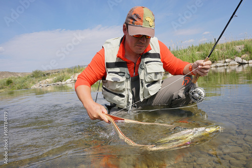 Fly fisherman in river of Montana catching brown trout