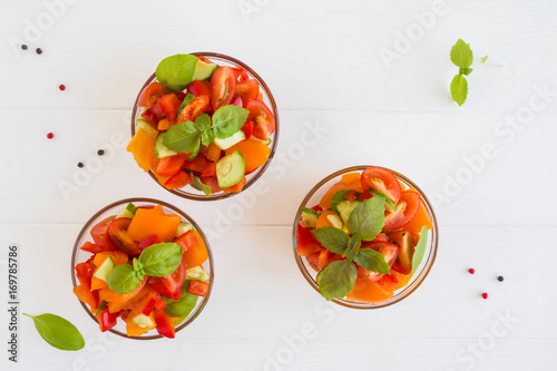 Healthy diet salad with fresh basil, red and yellow tomatoes, bell pepper in the small glass bowls, top view.