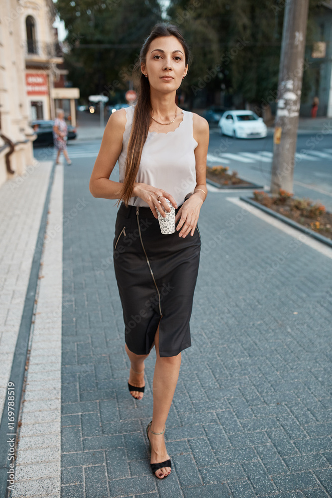 Beautiful brunette young woman walking through the streets of Old City. Fashion concept Beautiful brunette young woman walking through the streets of Old City. Fashion concept
