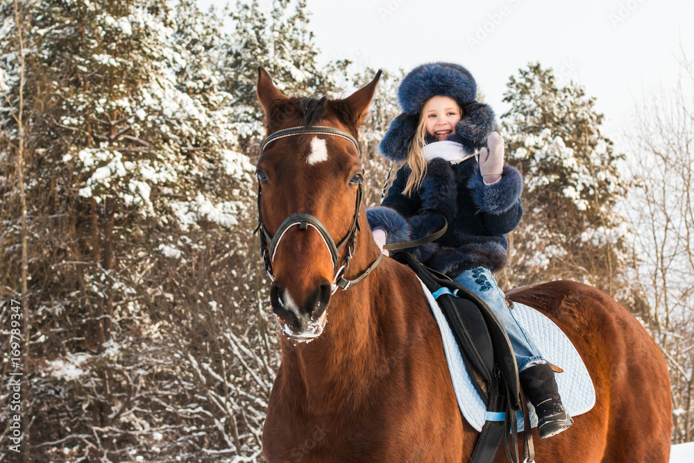 Fototapeta premium Small girl and horse in a winter