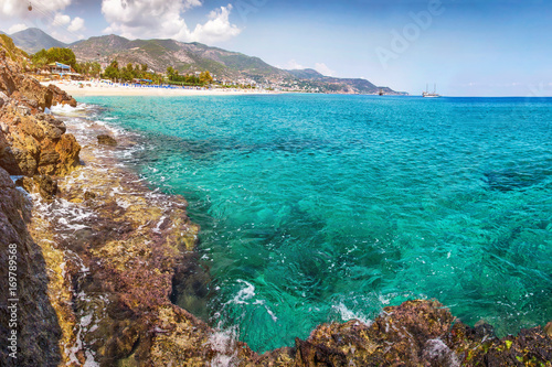Lagoon sea beach landscape. Paradise seascape, Turkey, vacation concept. Alanya beach with rock in clean water and mountains on horizont.