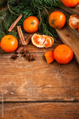 Tangerines (mandarins) with christmas tree branches with spices on wooden background. Copy space.