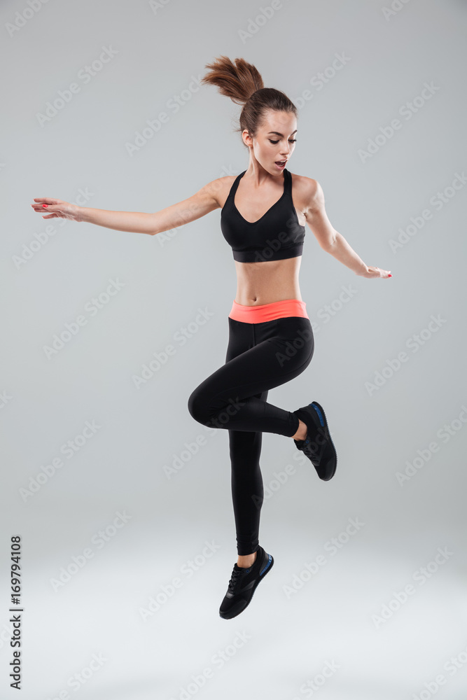 Full length image of a sports woman jumping in studio