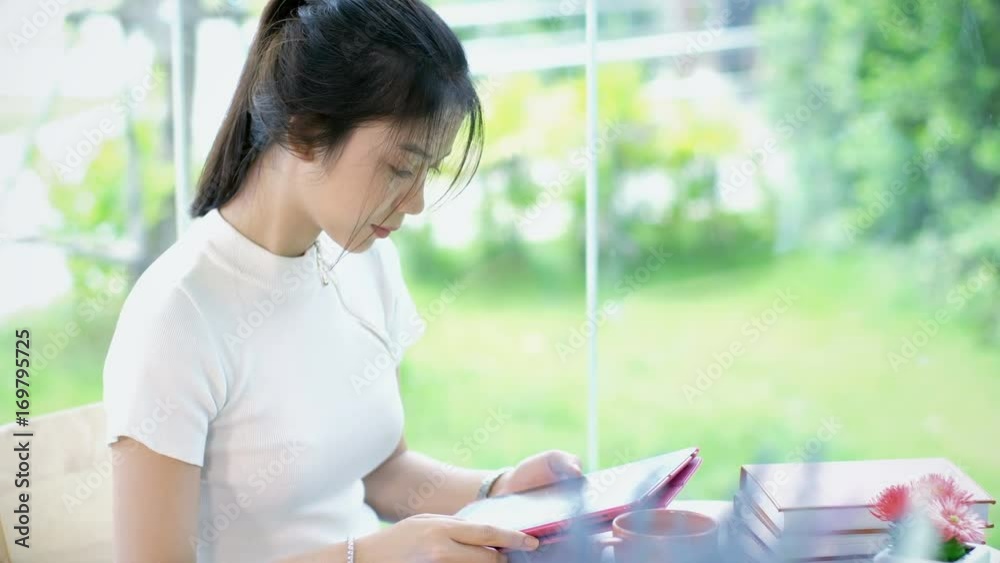 close up Asian teenage typing on tablet in garden close up Asian teenage typing on tablet in garden