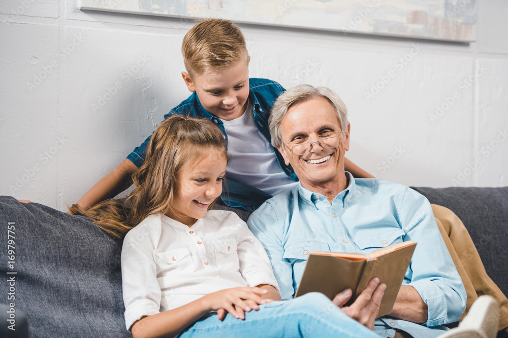family using laptopgrandfather and grandchildren reading book family using laptopgrandfather and grandchildren reading book