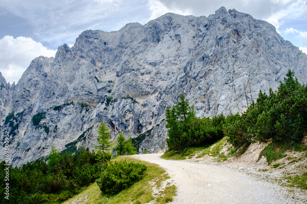 Old gravel road over Vrsic pass to Soca valley. Prisank - prisojnik, mountain with Pagan girl face in the background.
