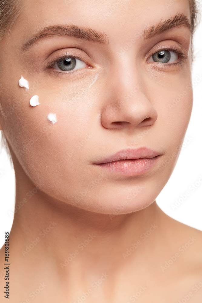 Obraz premium Gorgeous beautiful woman with cream face drops on her face. Studio photo. Beauty and skin care