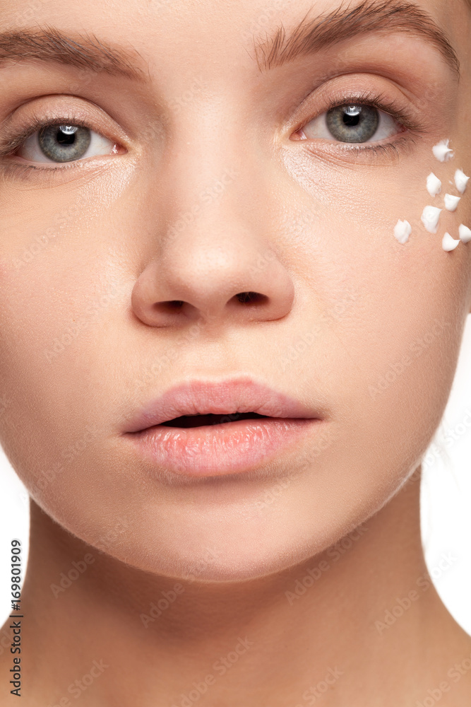 Beautiful woman with cream face drops on her face. Studio photo. Beauty and skin care Beautiful woman with cream face drops on her face. Studio photo. Beauty and skin care