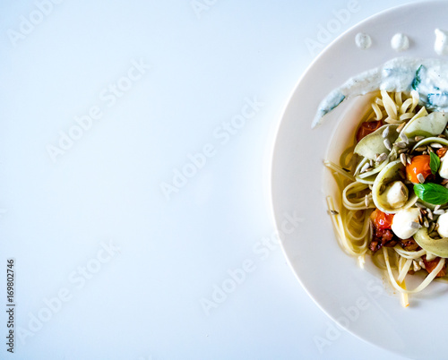 Top view of a pasta dish with mozzarella, tomatoes and basil.