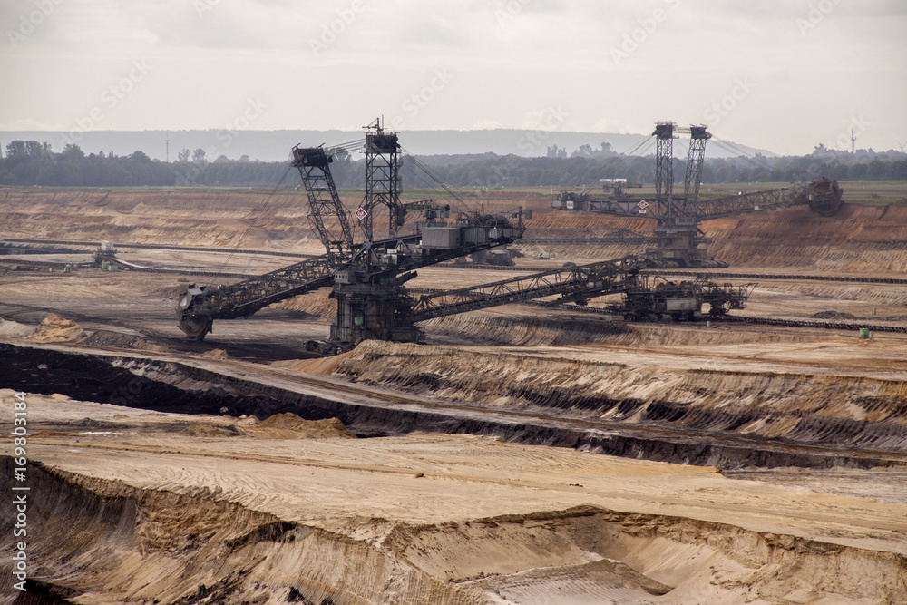 Germany, North Rhine Westphalia, -june 2017: ground excavator in action moving mullock and soil at open pit coal mine; Germany,for winning brown coal Germany, North Rhine Westphalia, -june 2017: ground excavator in action moving mullock and soil at open pit coal mine; Germany,for winning brown coal