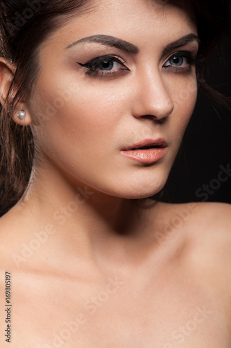 Beautiful gorgeous brunette model in studio photo on black background. Perfect make up and hairstyle