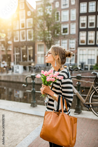 Photography Lifestyle portrait of a woman walking with bouquet of pink tulips near the water