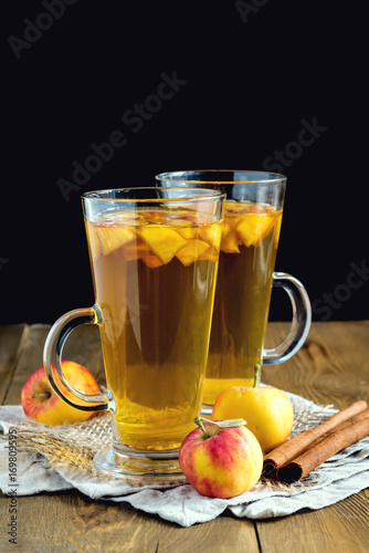 Two cups of tea with apple and spices on wooden background Vertical