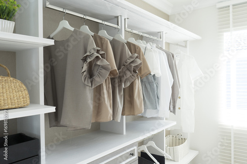 White wardrobe with shirts and pants hanging  photo