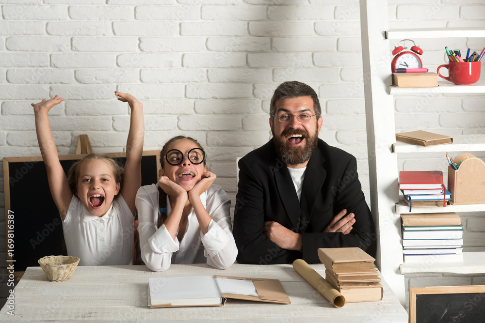Fototapeta premium Girls and bearded man sit at desk with books