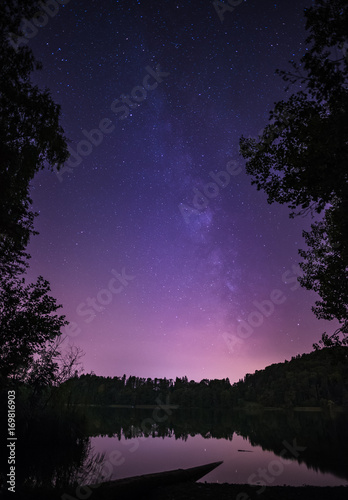 Milky way in the night sky above the horizon on a small lake in Switzerland