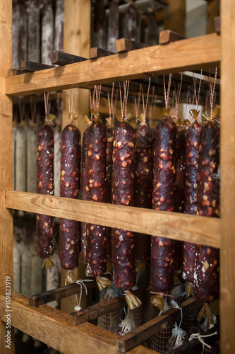 Aging dry-smoked sausages sticks on wooden container