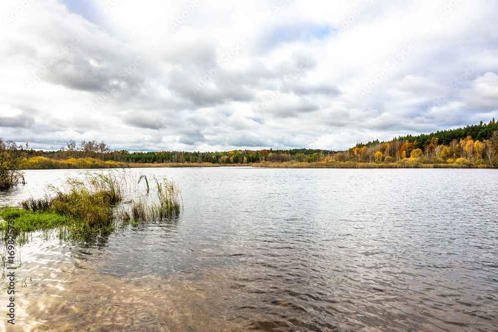 Cloudy autumn landscape with lake and forest