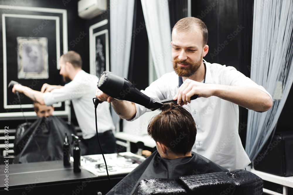Master cuts hair of a boy in the barbershop, hairdresser makes hairstyle for a boy Master cuts hair of a boy in the barbershop, hairdresser makes hairstyle for a boy