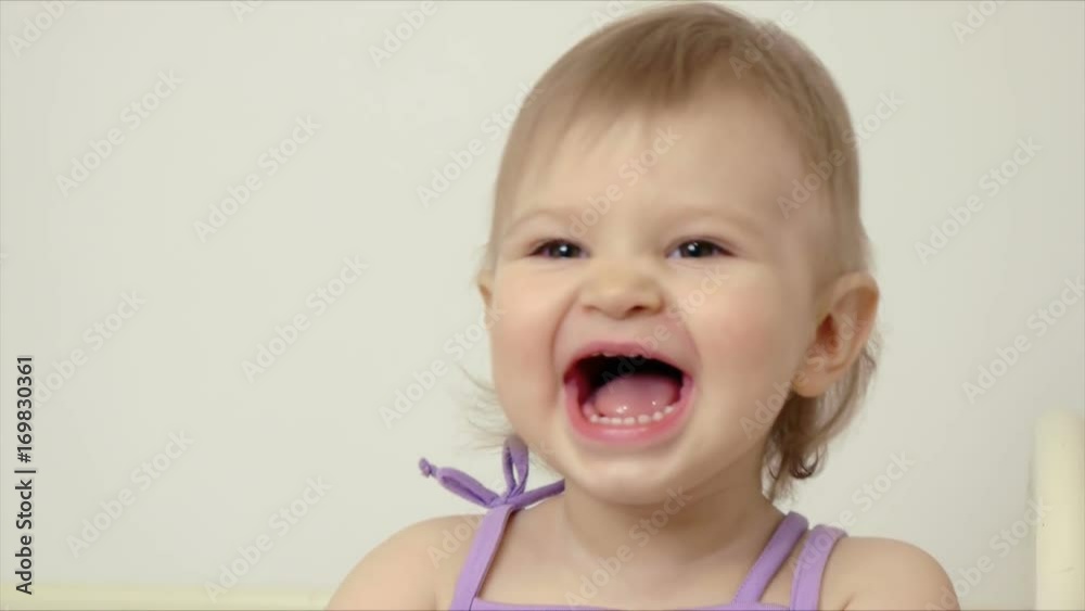 Cute little girl standing on a bed laughing happily and clapping her hands Cute little girl standing on a bed laughing happily and clapping her hands