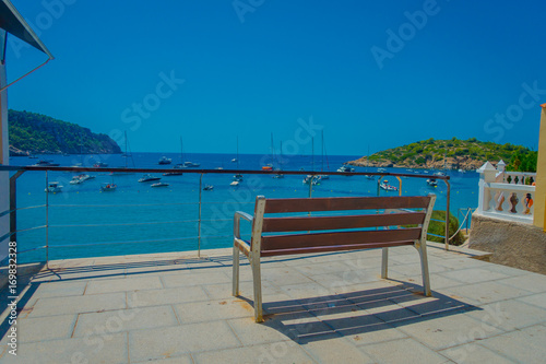 Beautiful sunny day in Sant Elm  with a public chair to enjoy the view in Majorca  with people enjoying the water  in Spain