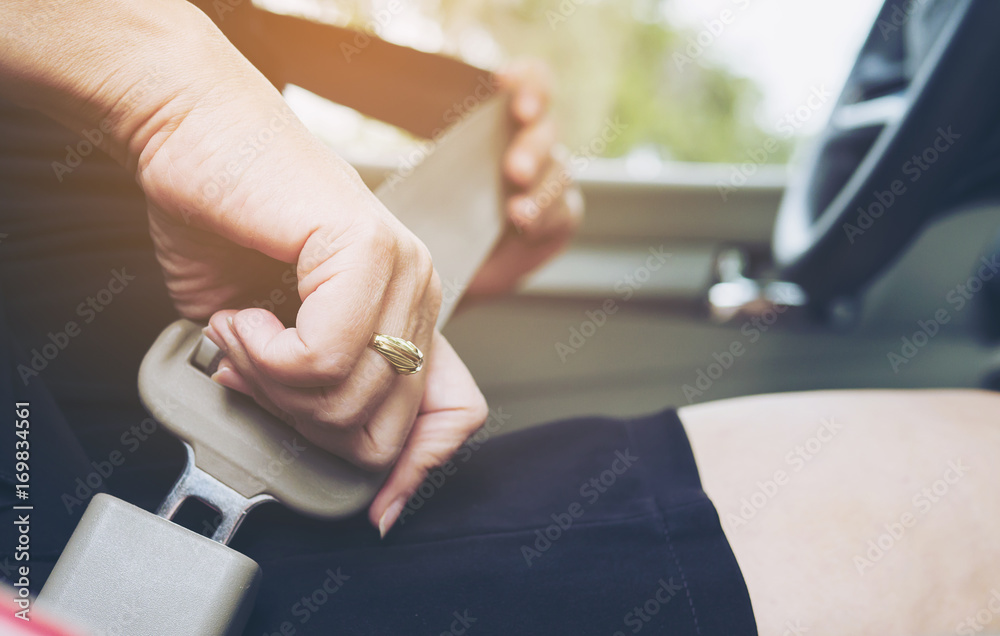 Lady putting car seat belt before driving, close up at belt buckle, safe drive concept