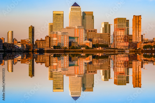 Golden sunset at Canary Wharf in London with cityscape reflection from river Thames