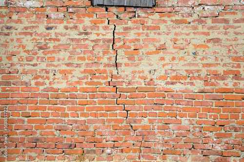 Red brick wall background with big crack