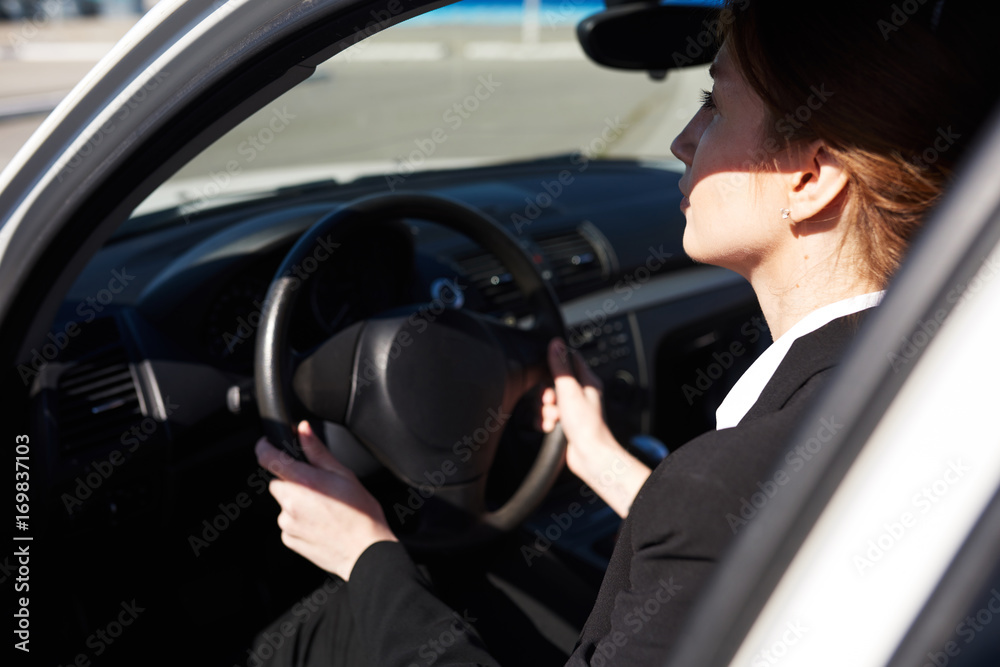Mid-age business woman working while being in the car Mid-age business woman working while being in the car