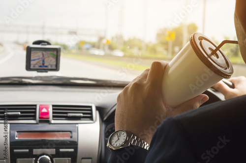 Man driving car using navigator and drinking coffee cup © pairhandmade