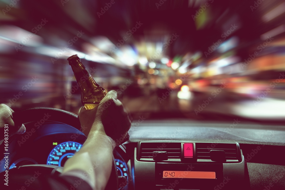 Fototapeta premium Man drink beer while driving at night in the city dangerously, left hand drive system