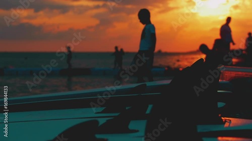Summer beach vacation at sunset, children, boys throwing stones at the water at sunset.