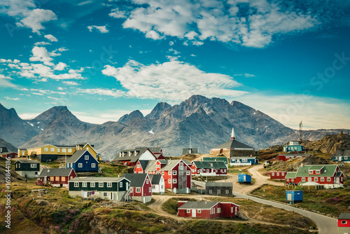 Small town on east coast of Greenland with colorful houses and mountain background photo