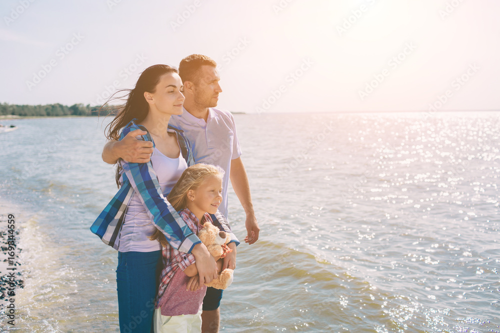 Happy family on the beach. People having fun on summer vacation. Father, mother and child against blue sea and sky background. Holiday travel concept Happy family on the beach. People having fun on summer vacation. Father, mother and child against blue sea and sky background. Holiday travel concept