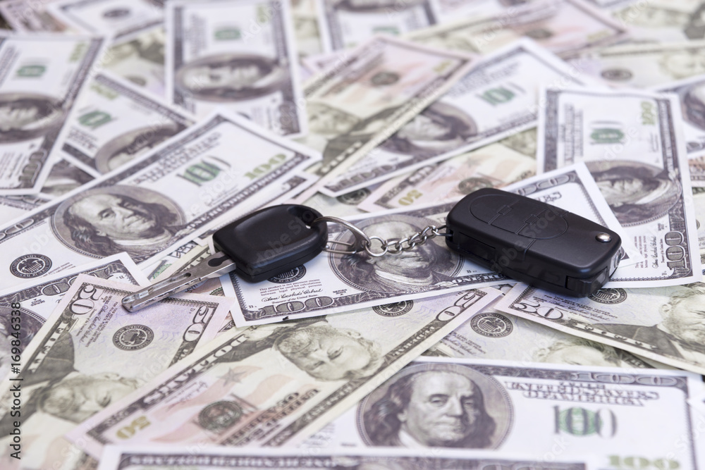 Keys with the car key ring on the background of the American dollar bills. Buying and selling a car. Car market. Keys with the car key ring on the background of the American dollar bills. Buying and selling a car. Car market.