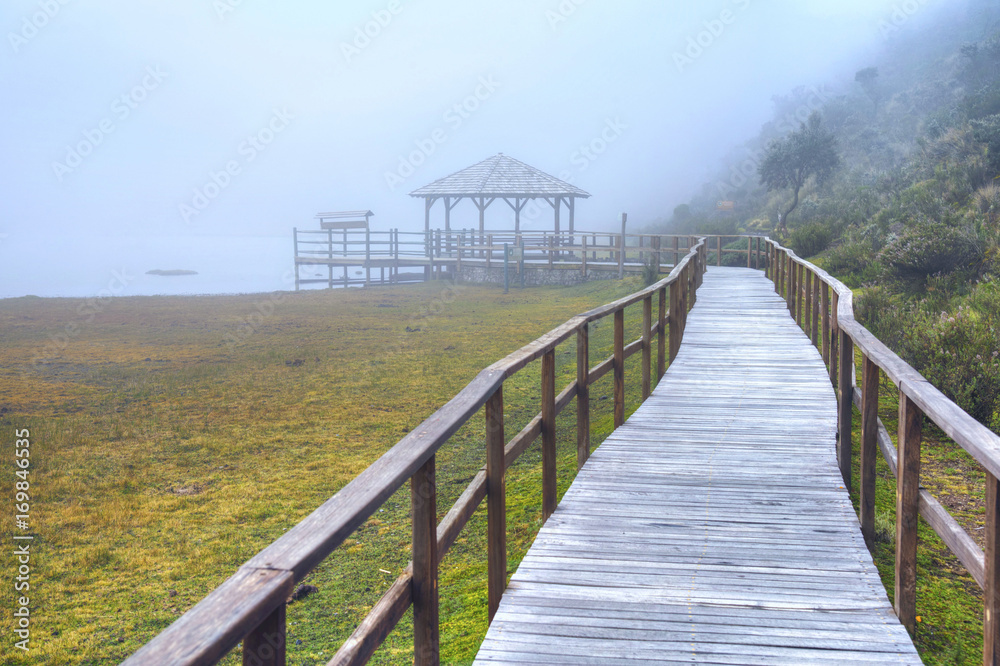 Wooden walkway that leads to the Limpiopungo Lake in the Cotopaxi National Park, on an overcast and foggy rainy day, Ecuador.