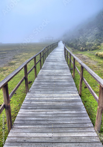 Wooden walkway that leads to the Limpiopungo Lake in the Cotopaxi National Park  on an overcast and foggy rainy day  Ecuador.