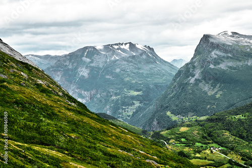 Close-up view of the mountains in western Norway with small villages and town at the bottom of the valley and summits covered with snow