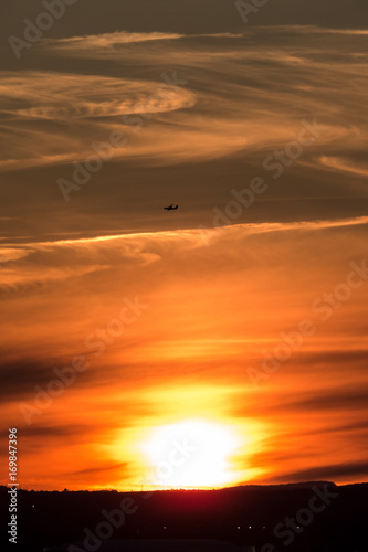 Bright vertical sunset with an airplane in the clouds. Quebec, Canada.