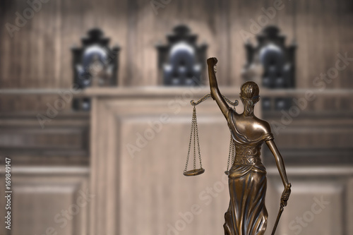Lady justice and empty bench with judge chairs in courtroom