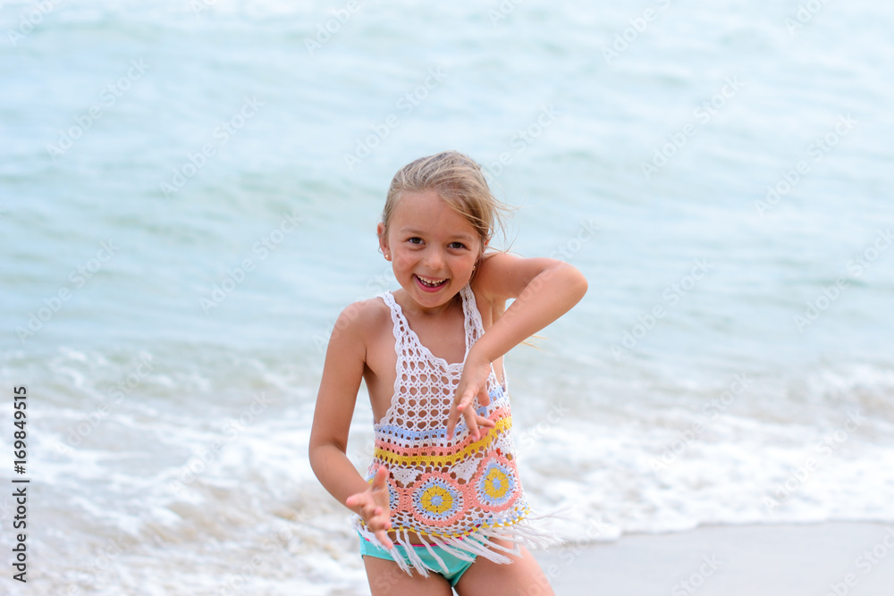 Cute happy smiling little girl play near the sea on a sunny summer day Cute happy smiling little girl play near the sea on a sunny summer day