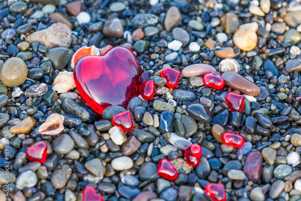 Fototapeta premium Pebble stones on the beach. Background of sea stones. stones with hearts. Red heart of the stones