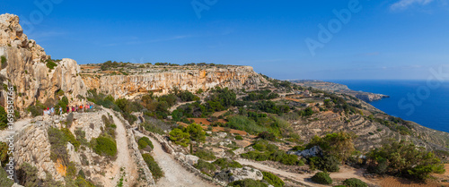 MALTA - OCTOBER 16, 2016: Group of hikers on limestone cliff of Southern shore of Malta island. Summer sunny day. Panoramic seascape.