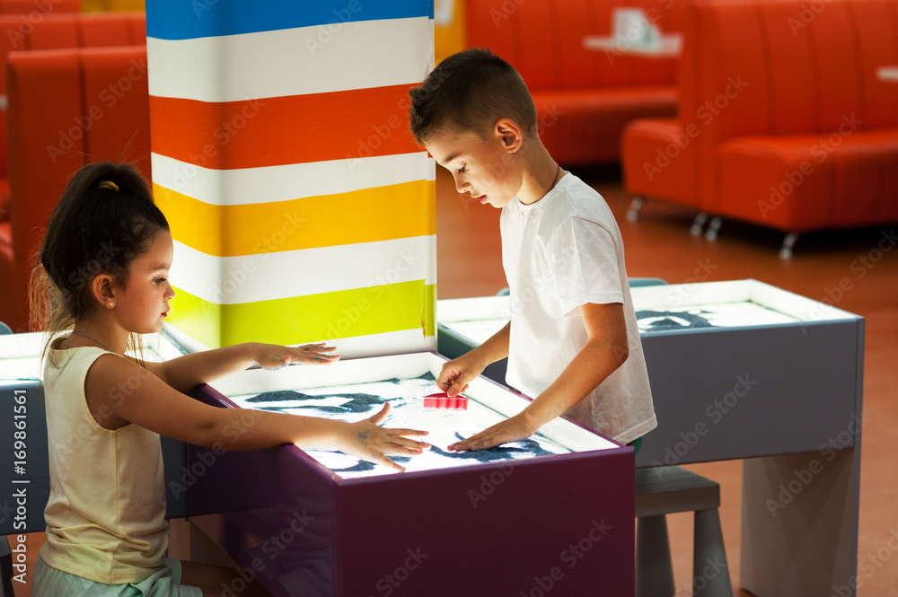 Naklejka premium A boy and a girl are painting with sand. Sand animation