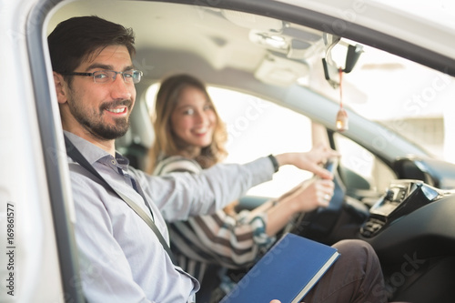 Driving instructor is teaching his student how to drive a car