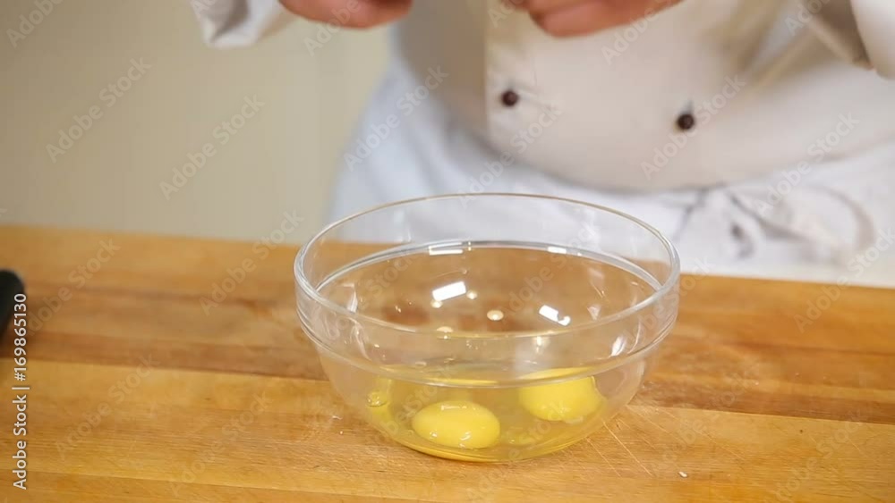 Breaking eggs into glass bowl Breaking eggs into glass bowl