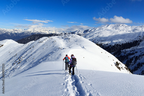 Man and woman hiking on snowshoes and mountain snow panorama with blue sky in Stubai Alps, Austria © johannes86