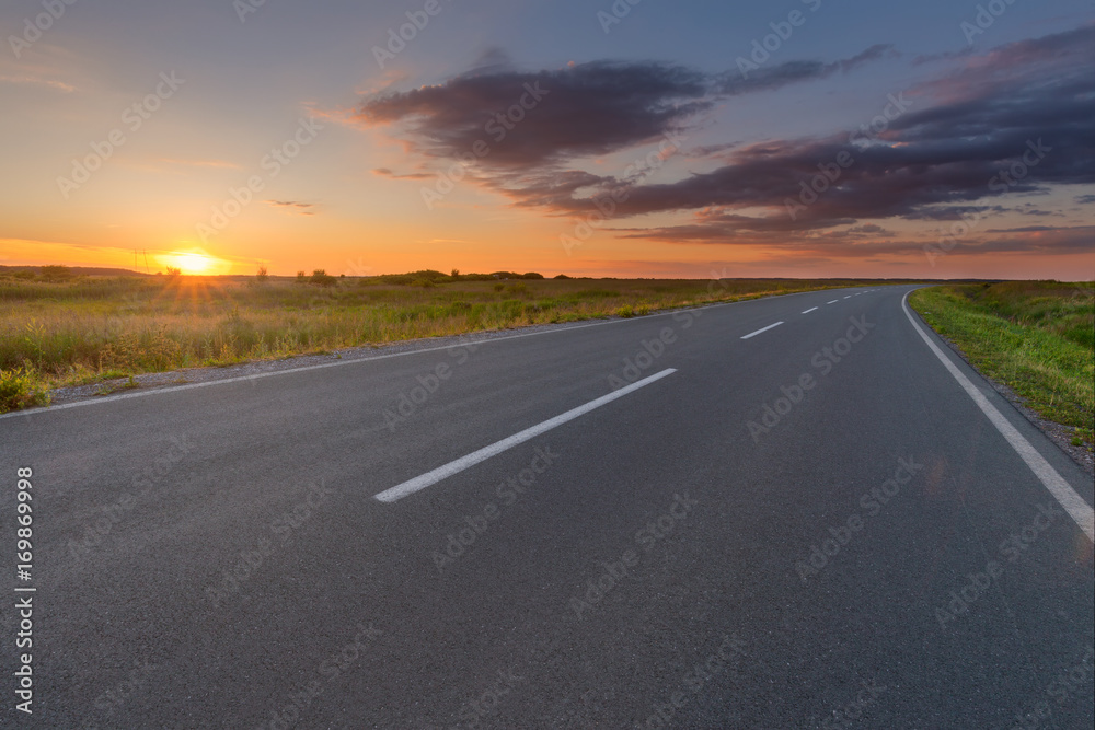 Curved asphalt road in plain at beautiful sunset