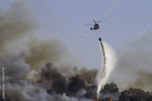 Wild fire close to houses being fought with airplanes and helicopters