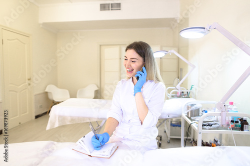 Beautiful female microblasting master conducts dialogue on cell  photo